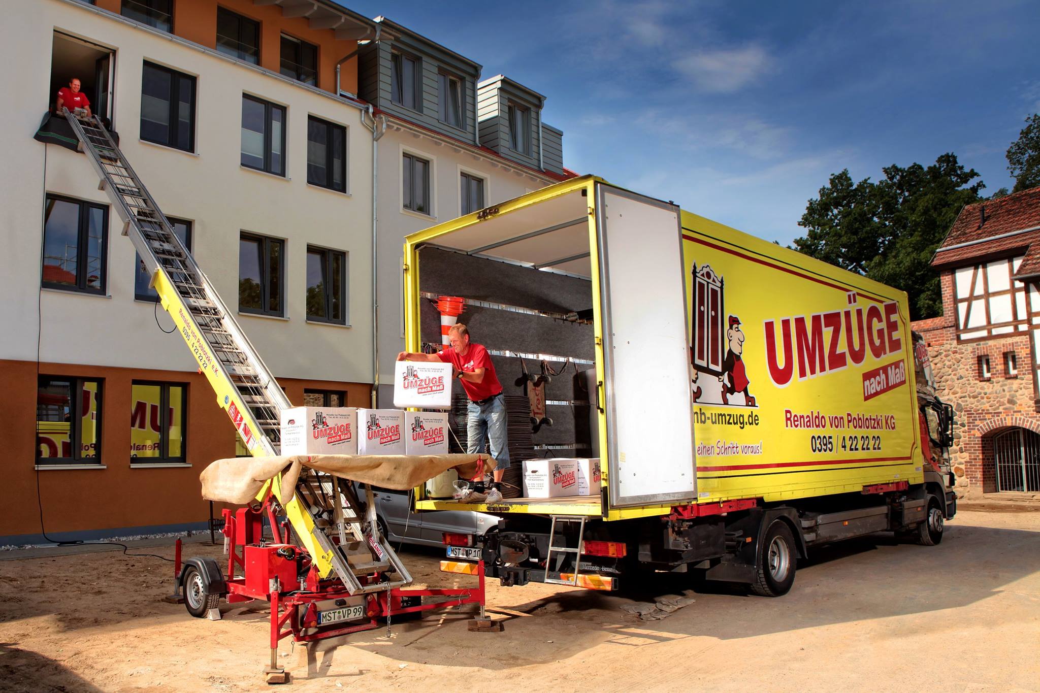 Umzugsteam mit gelbem Möbelwagen und Außenaufzug im Einsatz
